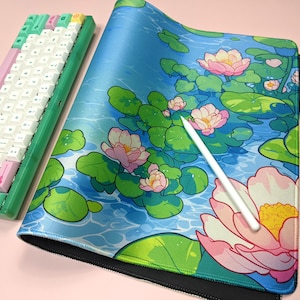 May include: A blue and green mousepad with a floral design featuring pink water lilies and green lily pads. The mousepad has a black border.