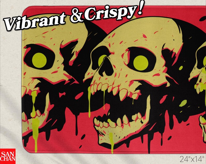 May include: A rectangular mat featuring a graphic design of two skulls with yellow eyes and teeth, set against a red background. The skulls have black outlines and dripping green accents. The text "Vibrant & Crispy!" is at the top. The mat measures 24" x 14".