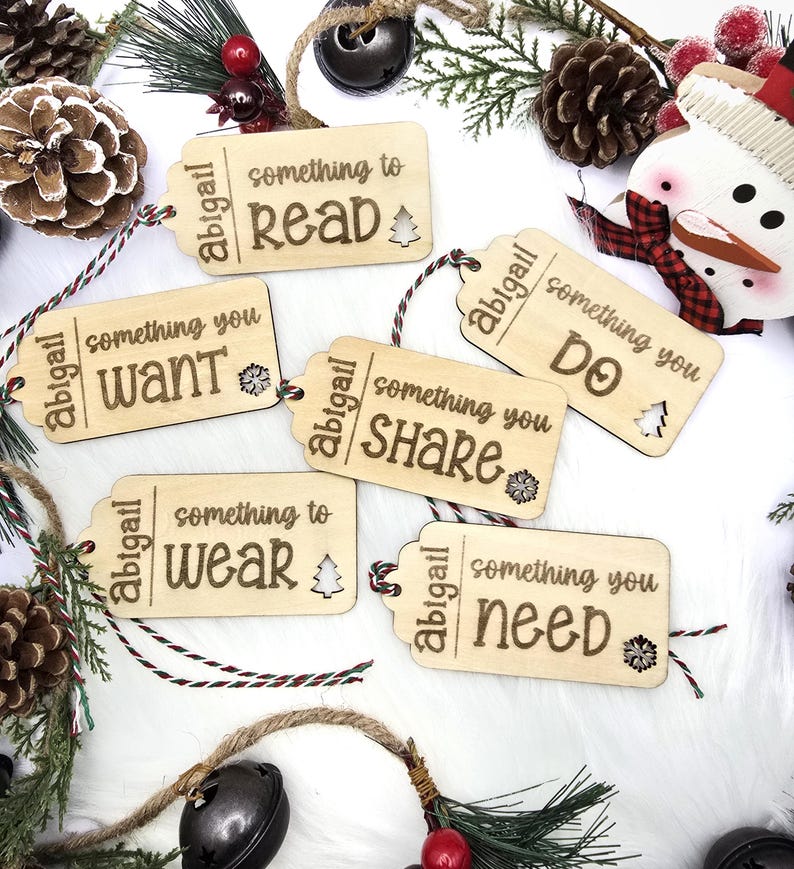 Pu&ograve; includere: Sei etichette regalo in legno con uno spago rosso e bianco. Ogni etichetta ha il nome "Abigail" e una frase diversa: "qualcosa da leggere", "qualcosa che vuoi", "qualcosa da indossare", "qualcosa da condividere", "qualcosa da fare" e "qualcosa di cui hai bisogno".