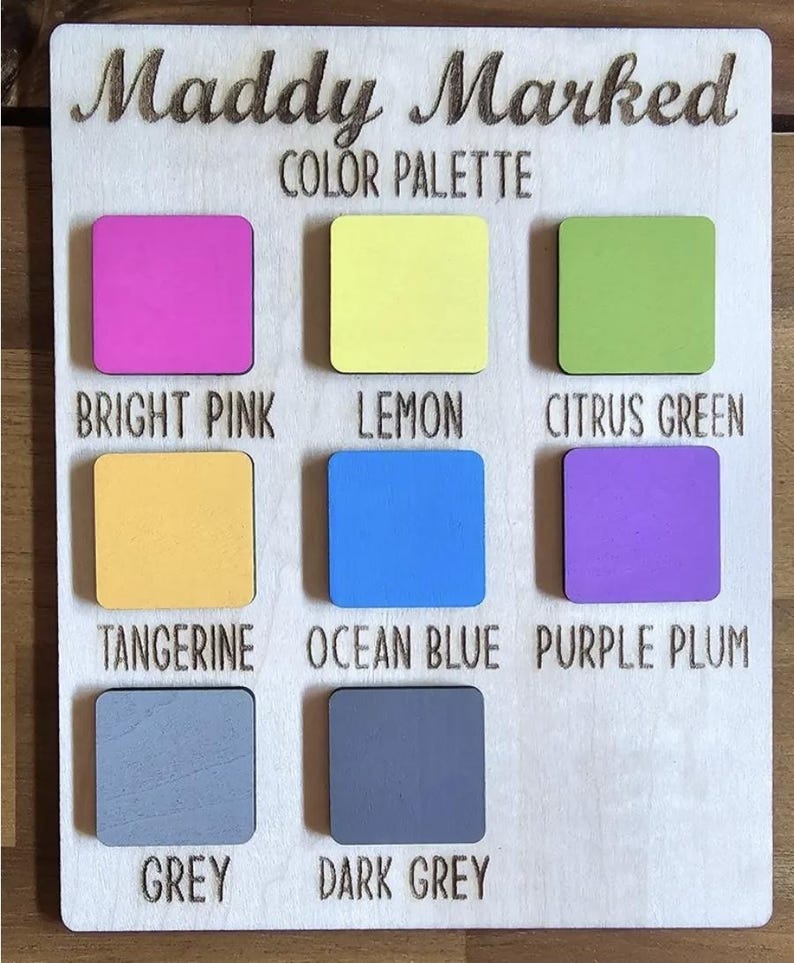 May include: Wooden color palette with the text "Maddy Marked COLOR PALETTE." The palette features nine color swatches in bright pink, lemon, citrus green, tangerine, ocean blue, purple plum, grey, and dark grey.