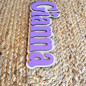 May include: Purple wooden sign with the word "Pumpkin" written in a whimsical font.