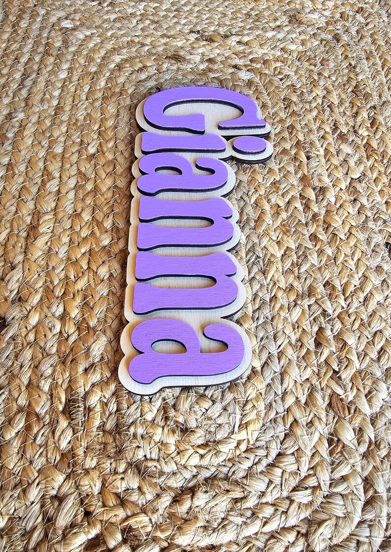May include: Purple wooden sign with the word "Pumpkin" written in a whimsical font.