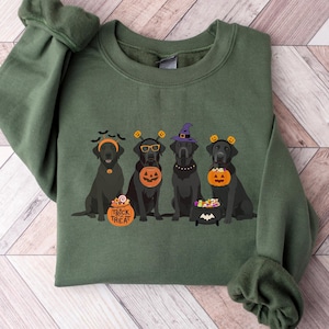 May include: Military green sweatshirt featuring a Halloween-themed design. The design includes four black Labrador retrievers wearing Halloween costumes, with the text "Trick or Treat". The sweatshirt is made of a soft material.