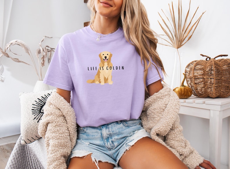 May include: A lavender t-shirt with a graphic of a golden retriever dog and the text "Life is Golden".