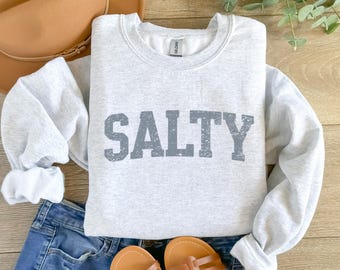 Könnte beinhalten: Ein grauer Pullover mit dem Wort "SALTY" in einem verwaschenen grauen Schriftzug.
