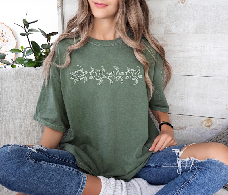 May include: A green t-shirt with a white outline of five sea turtles in a row.