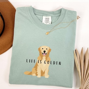 May include: A light green t-shirt with a golden retriever illustration and the text "Life is Golden".