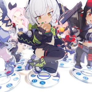 May include: Acrylic anime character standees featuring various characters. The central figure is a girl with white hair, headphones, and a green and black outfit, eating a burger. Other characters are visible in the background, each on a circular base.