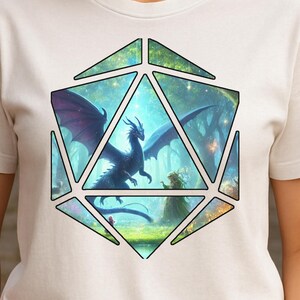 Puede incluir: Una camiseta blanca con un diseño de fantasía. El gráfico es una forma multifacética con un dragón y una figura en un bosque. El dragón tiene alas moradas y un cuerpo azul oscuro. El fondo es una mezcla de verde y azul.