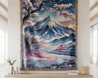 May include: A woven tapestry depicting a watercolour landscape of a mountain range, cherry blossoms, and a serene lake. The artwork is in shades of blue, purple, and pink, with a fringed border. The tapestry is displayed on a wall.