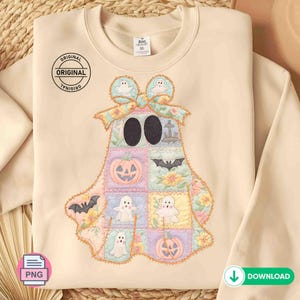 May include: Beige sweatshirt featuring a patchwork ghost design with Halloween-themed squares. The ghost has large black eyes and is adorned with a bow. The squares include pumpkins, bats, and ghosts. The sweatshirt has the word "ORIGINAL" printed on it.
