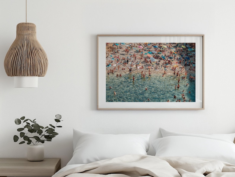 May include: An aerial view of a crowded beach with people swimming and sunbathing in the turquoise water. The beach is covered in colorful umbrellas and towels.