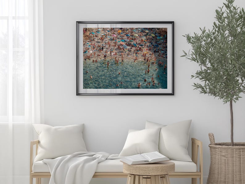 May include: An aerial view of a crowded beach with people swimming and sunbathing in the turquoise water. The beach is covered in colorful umbrellas and towels.