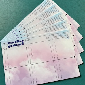 May include: A set of six blank travel postcards with a pink and purple watercolor cloud design. The postcards have a section for name, date, and place. The text "traveling postcard" is printed at the top of the card.