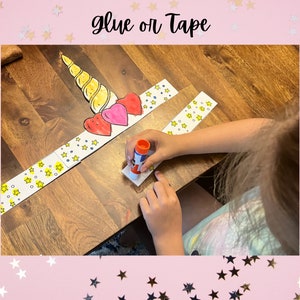 Peut inclure: Un enfant fabrique un bricolage de licorne en utilisant de la colle et du papier. Le bricolage est compos&eacute; d'une corne de licorne, de c&oelig;urs et d'&eacute;toiles. Les mots "glue or tape" sont &eacute;crits en haut de l'image.