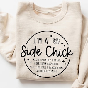 May include: A beige sweatshirt with a black circle graphic that says "I'm a Side Chick" with a turkey illustration and the text "Mashed potatoes & gravy, green bean casserole, stuffing, rolls, candied yams & cranberry sauce."