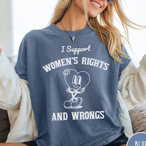 May include: A blue jean t-shirt with white text that reads "I Support Women's Rights and Wrongs". The text is surrounded by a cartoon heart with a flower on top.