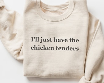 May include: A beige sweatshirt with the text "I'll just have the chicken tenders" printed on the front.