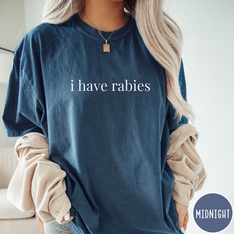 May include: A navy blue t-shirt with the phrase "i have rabies" printed in white. The shirt has a relaxed fit and short sleeves. The shirt is part of a Midnight collection.