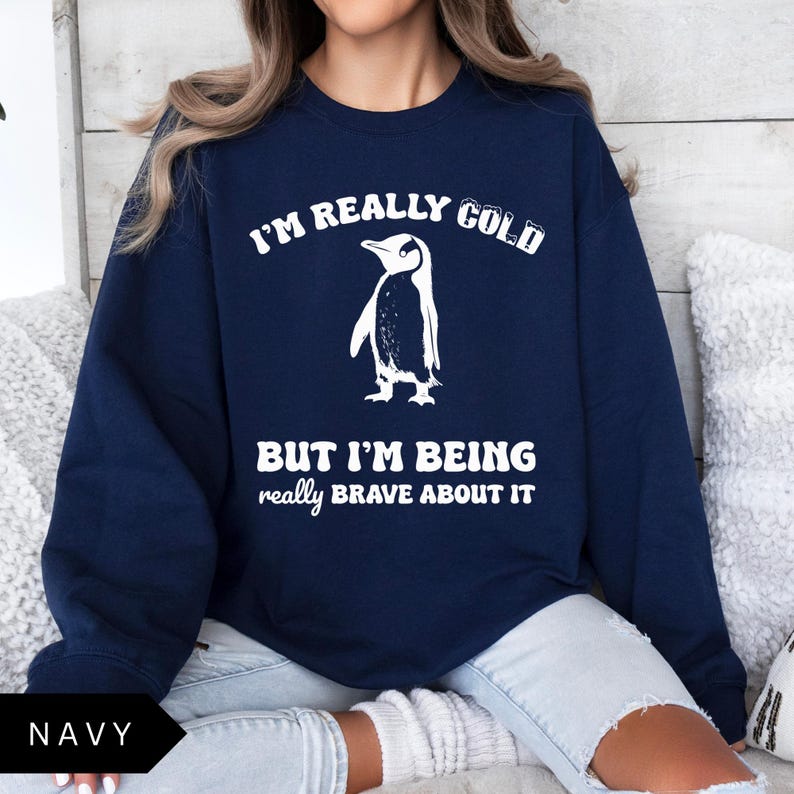 May include: A navy blue sweatshirt with a white penguin graphic and the text "I'm really cold but I'm being really brave about it".