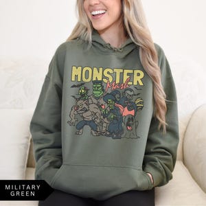 Puede incluir: Una sudadera con capucha verde con el texto "Monster Mash" impreso en la parte delantera. El gr&aacute;fico presenta un grupo de monstruos de dibujos animados en un entorno espeluznante.