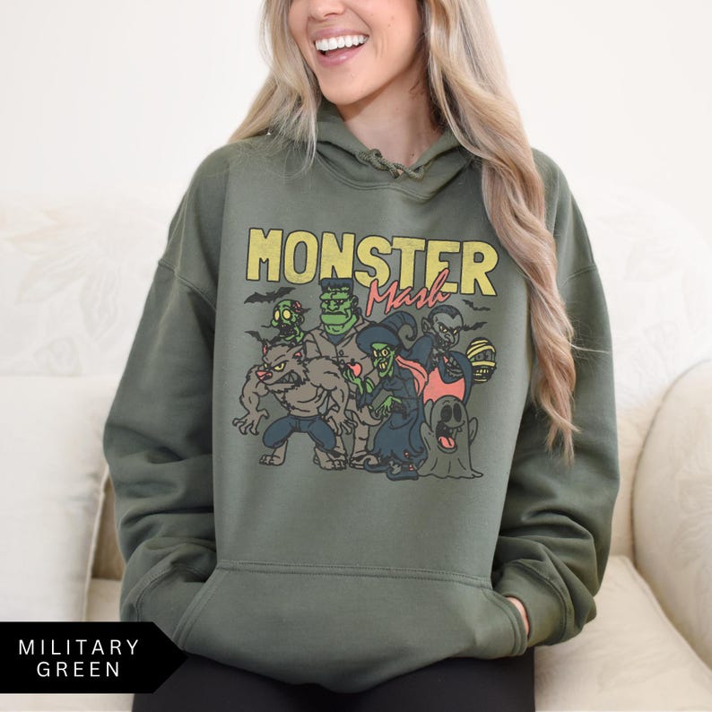 Puede incluir: Una sudadera con capucha verde con el texto "Monster Mash" impreso en la parte delantera. El gr&aacute;fico presenta un grupo de monstruos de dibujos animados en un entorno espeluznante.