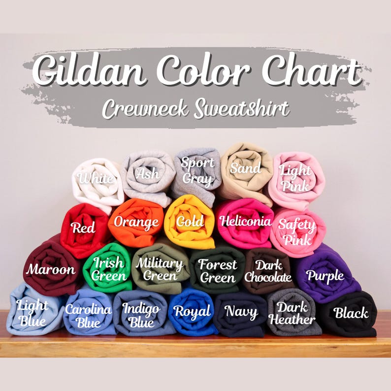 May include: A Gildan Color Chart for crewneck sweatshirts featuring twenty-four rolled fabric samples in various colors including white, ash, sport gray, sand, light pink, red, orange, gold, heliconia, safety pink, maroon, irish green, military green, forest green, dark chocolate, purple, light blue, carolina blue, indigo blue, royal, navy, dark heather, and black.