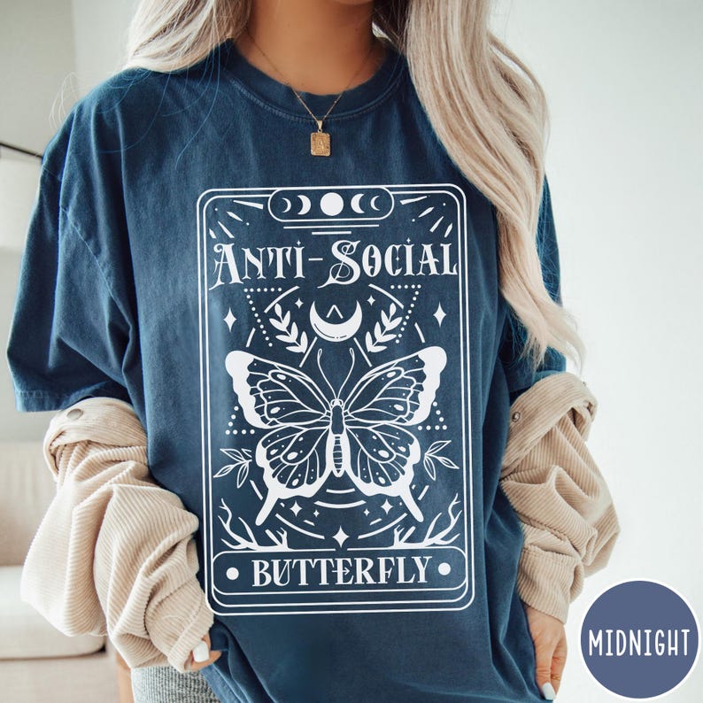 Puede incluir: Una camiseta azul marino con un gr&aacute;fico blanco de una mariposa y el texto "Anti-Social Butterfly".