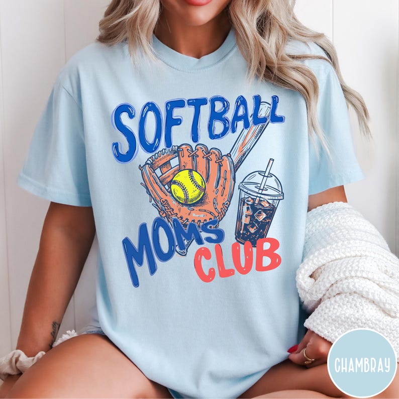 May include: Light blue t-shirt with the words "SOFTBALL MOMS CLUB" in blue and red. The design includes a softball glove, a yellow softball, and a drink with ice. The shirt is a casual wear item.