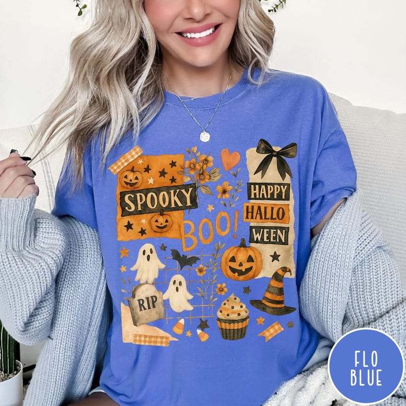 Op de afbeelding: Blauw T-shirt met een Halloween-thema. Het ontwerp bevat pompoenen, geesten, een heksenhoed en de zinnen "Spooky", "Boo!" en "Happy Halloween". Het shirt heeft een relaxte pasvorm en is gemaakt van een zachte stof.
