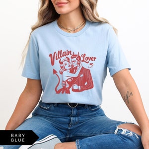May include: A light blue t-shirt with a red graphic of a couple in a vintage style. The text "Villain Lover" is printed in red above the graphic.