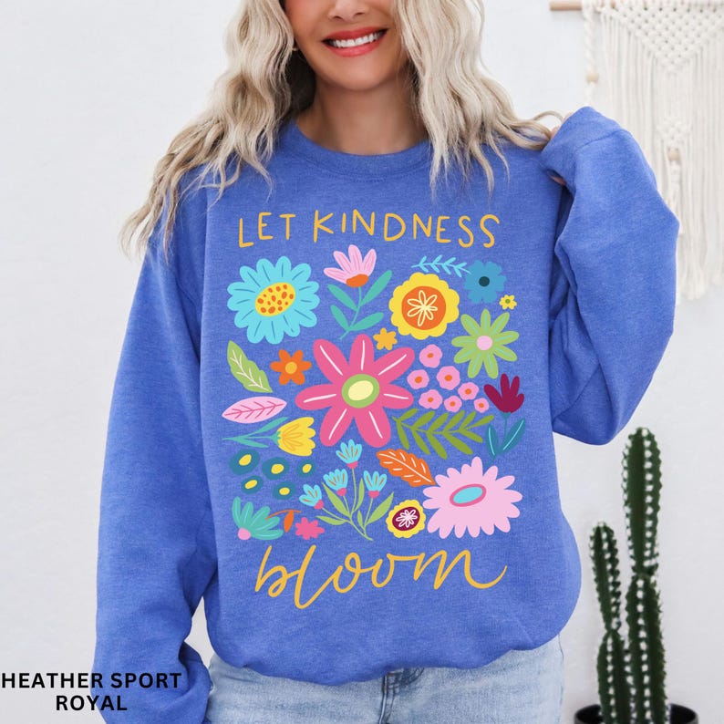 May include: A royal blue sweatshirt with a floral design and the text "Let kindness bloom" in yellow.
