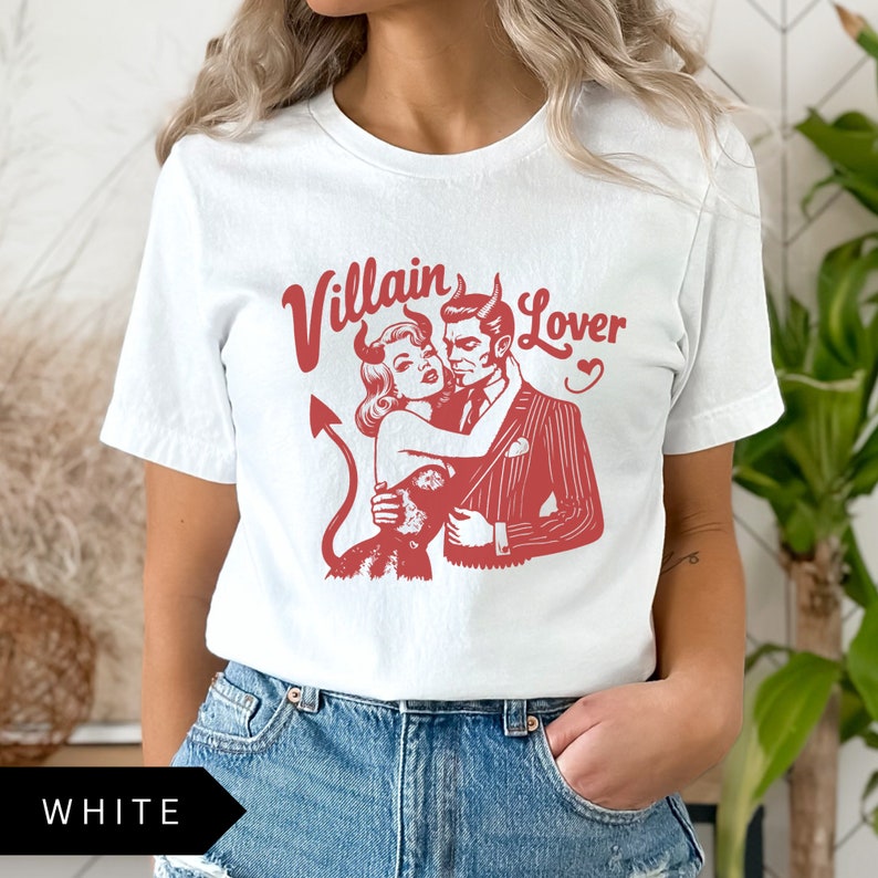 May include: White t-shirt with a red graphic of a devil couple with the text "Villain Lover" printed on it.