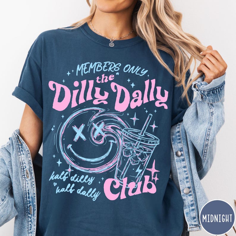 May include: Navy blue t-shirt with a graphic design. The design features the text "MEMBERS ONLY the Dilly Dally Club" in pink and blue, along with a smiley face and a drink. The words "half dilly half dally" are also included.