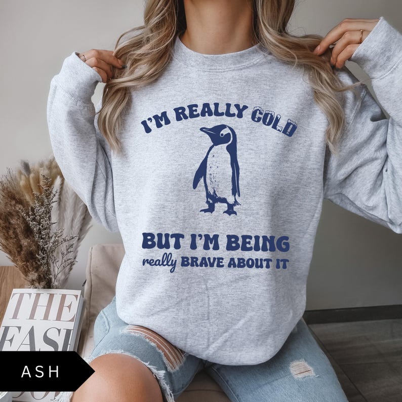 May include: A gray sweatshirt with a blue penguin graphic and the text "I'm really cold but I'm being really brave about it."