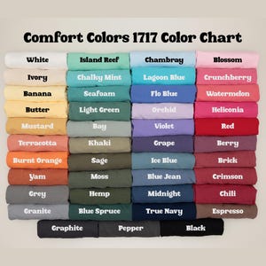 Puede incluir: Una carta de colores Comfort Colors 1717 que muestra muestras de tela dobladas en varios tonos. El texto dice Comfort Colors 1717 Color Chart, seguido de etiquetas para colores como White, Ivory, Banana, Butter, Mustard, Terracotta, Burnt Orange, Yam, Grey, Granite, Island Reef, Chalky Mint, Seafoam, Light Green, Bay, Khaki, Sage, Moss, Hemp, Blue Spruce, Graphite, Pepper, Chambray, Lagoon Blue, Flo Blue, Orchid, Violet, Grape, Ice Blue, Blue Jean, Midnight, True Navy, Blossom, Crunchberry, Watermelon, Heliconia, Red, Berry, Brick, Crimson, Chili, Espresso y Black.