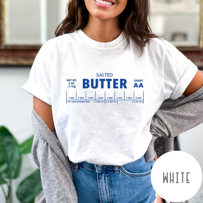 May include: White t-shirt with a blue graphic of a stick of butter with the text "SALTED BUTTER GRADE AA" and a measurement guide for tablespoons and cups. The text "NET WT. 4 OZ. (113g)" is also included.