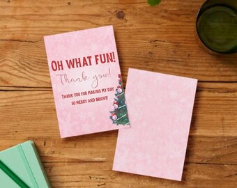 May include: Two pink greeting cards with text that reads "OH WHAT FUN! Thank you! THANK YOU FOR MAKING MY DAY SO MERRY AND BRIGHT!" One card has a Christmas tree graphic. The cards are on a wooden surface.