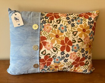 Peut inclure: Un oreiller décoratif avec un motif floral bleu et blanc d'un côté et un tissu bleu uni avec trois boutons dorés de l'autre.
