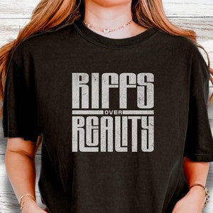 May include: Black t-shirt with a white graphic that says "Riffs Over Reality" in a bold, blocky font.