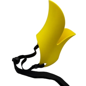 May include: A bright yellow muzzle with a curved design and a black adjustable strap. The muzzle is made of a solid material and features a contoured shape. The black strap has a buckle for secure fitting.