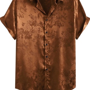 以下が含まれることがあります： 花柄のプリントが施された、茶色のサテン地の半袖ボタンダウンシャツです。
