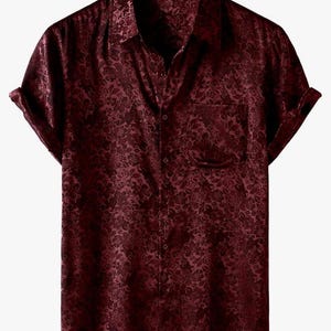 May include: A burgundy short-sleeve shirt with a floral pattern. The shirt has a button-down front, a chest pocket, and rolled-up sleeves. The fabric has a subtle sheen, and the overall style is classic and versatile.