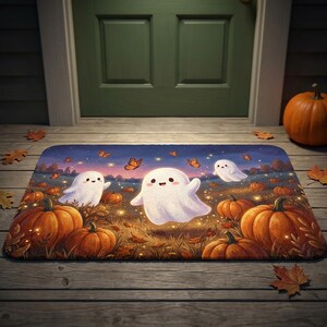 Puede incluir: Un felpudo rectangular con una ilustración de tres fantasmas blancos flotando sobre un campo de calabazas al atardecer. La escena incluye calabazas naranjas, hojas de otoño dispersas y mariposas naranjas sobre un cielo azul oscuro.