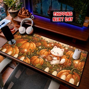 Peut inclure: Un tapis de bureau rectangulaire orné d'un motif de citrouilles orange, de vignes vertes et d'un chat blanc de dessin animé portant une écharpe orange et tenant un petit arrosoir. Le tapis est posé sur un bureau en bois avec une souris blanche.