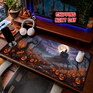 Könnte beinhalten: Eine rechteckige Schreibtischunterlage mit einer dunklen, atmosphärischen Halloween-Szene, die ein Spukschloss, einen Vollmond und zahlreiche leuchtende Kürbisse auf einem Waldboden mit kahlen Bäumen und herbstlichem Laub zeigt.