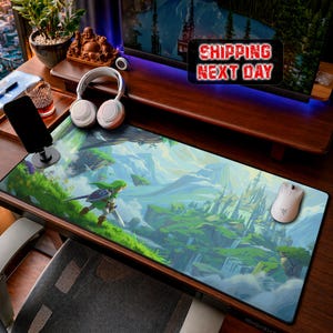 May include: A rectangular desk mat featuring a vibrant, illustrated landscape of a green-clad warrior standing on a grassy cliff overlooking a distant castle, with white wireless headphones and a white computer mouse placed on the surface.
