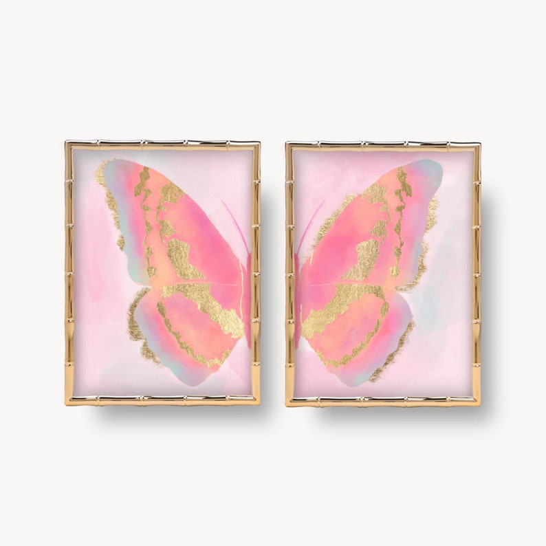 Puede incluir: Dos impresiones enmarcadas de mariposas rosas con detalles dorados sobre un fondo blanco. Las mariposas est&aacute;n en un marco de bamb&uacute; dorado.