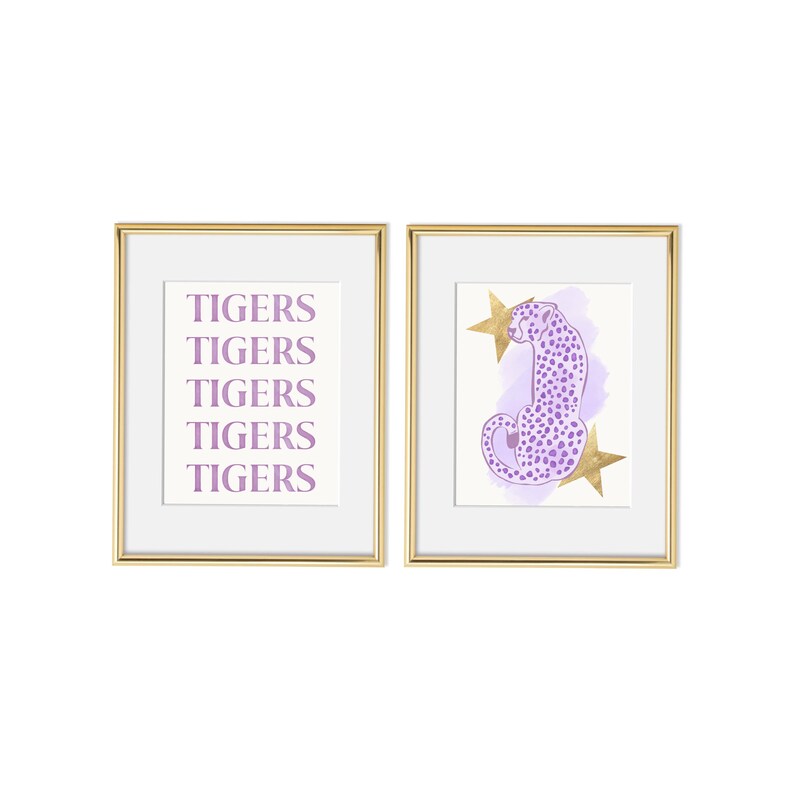 May include: Two framed prints with a gold frame. The print on the left has the word "TIGERS" repeated five times in a light purple color. The print on the right has a purple cheetah with gold stars on a light purple background.