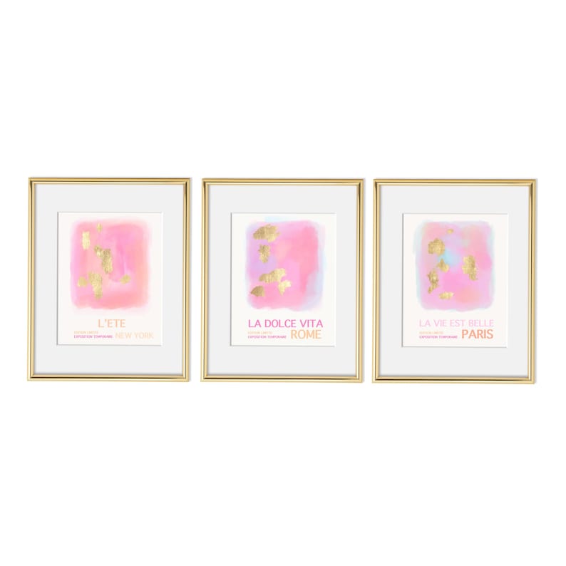 May include: Three framed prints with pink watercolor backgrounds and gold foil accents. The prints feature the text "L'ete New York", "La Dolce Vita Rome", and "La Vie Est Belle Paris".